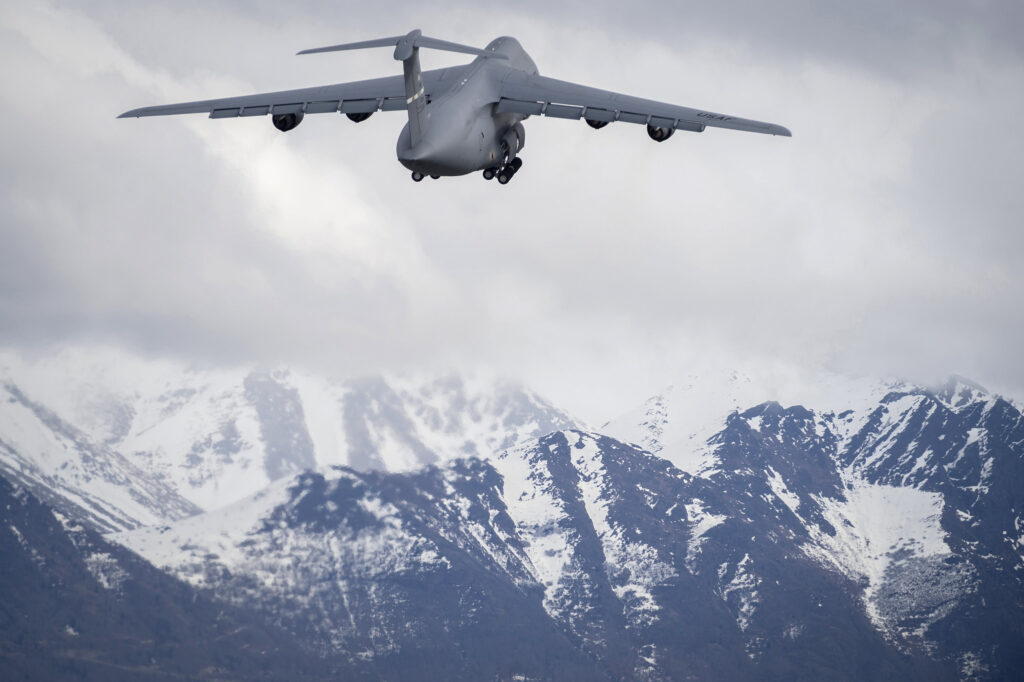 The C-5 galaxy taking off towards some snow tipped mountains.