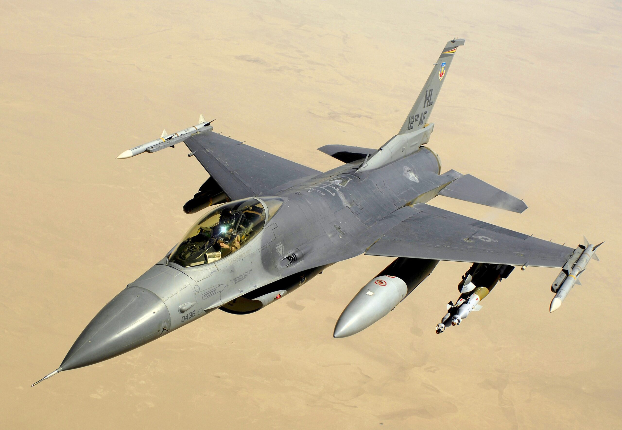An F-16C flying through the air above the desert.