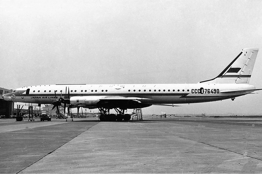 A side on photograph of a Tu-114 airliner parked at an airport.