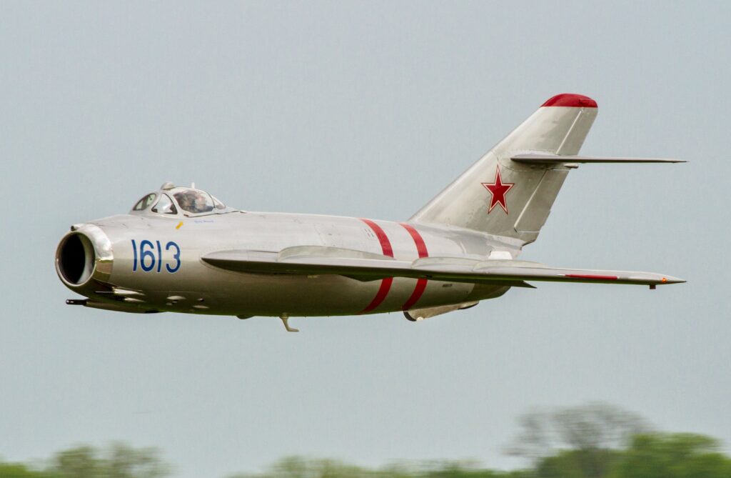 MiG 17 in low level flight above some tree tops.