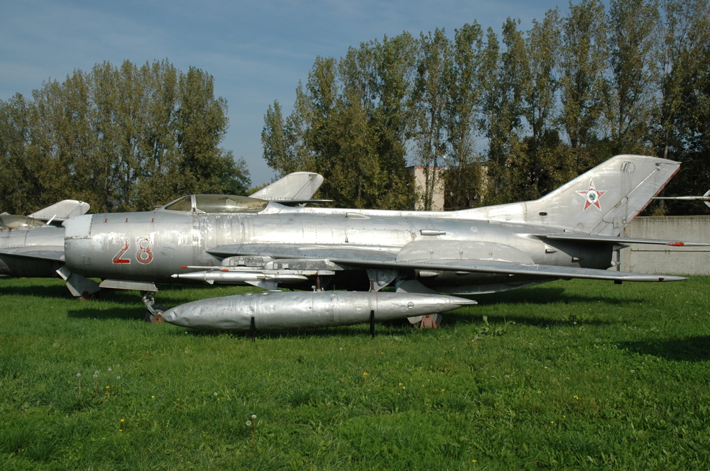 A side photo of a Hungarian MiG 19 parked outside.