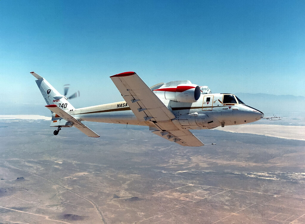 A S-72 in pure aircraft configuration flying against a blue sky and banking away to the left.