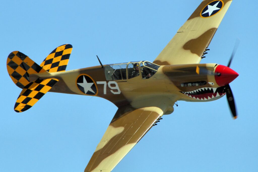 A P-40 banking to the right against a blue sky.